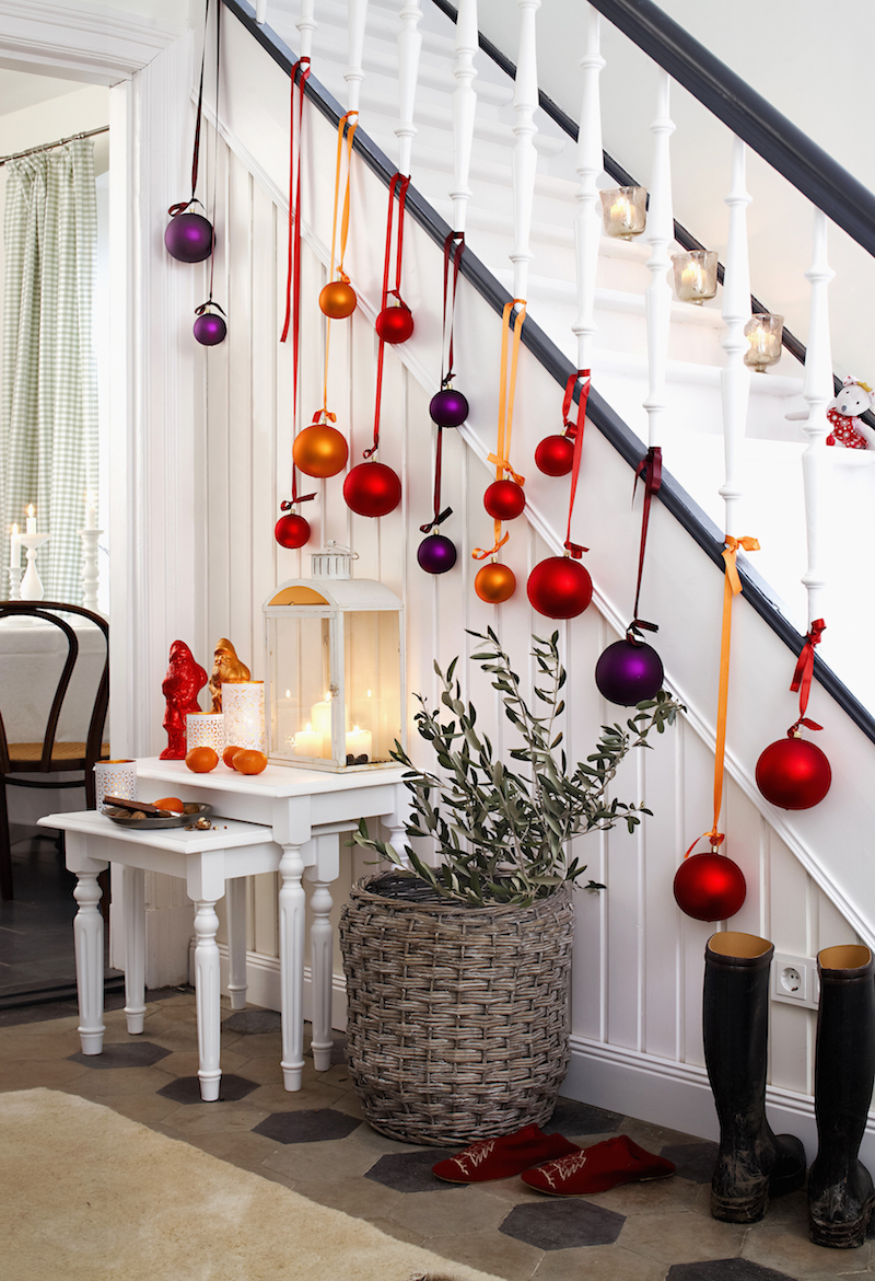 A banister and hallway decorated with Christmas baubles and candles